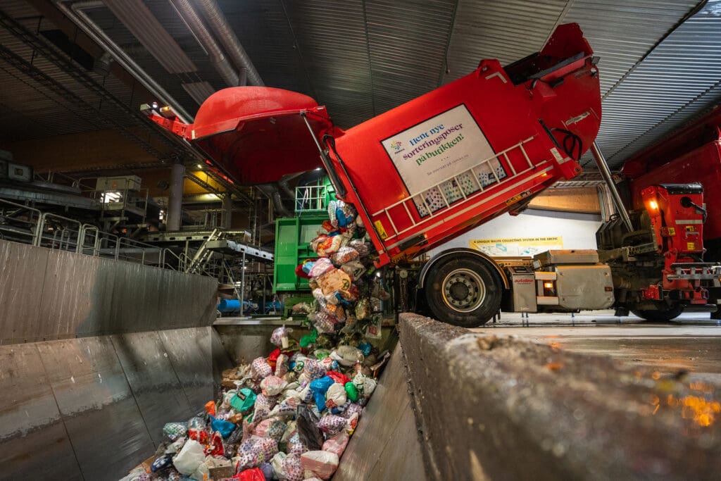 Bide av renovasjonsbil som tømmer sortert avfall i grava